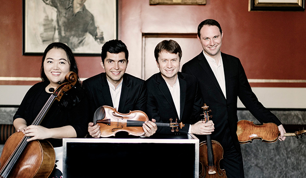 Group portrait of the Calidore String Quartet with their instruments.