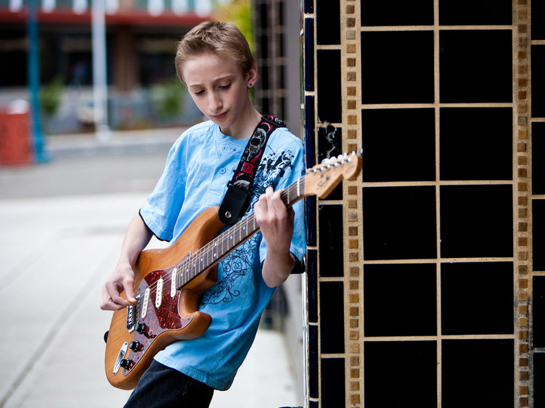 Photo of a young boy playing an electric guitar.
