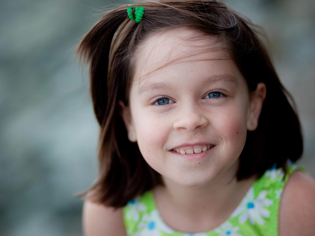Close up photo of a young girl in a green dress.