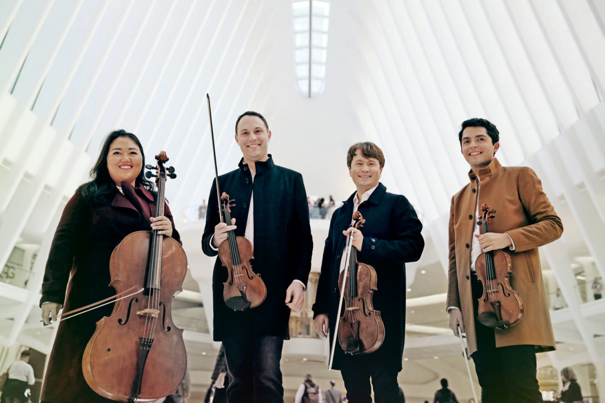 Photo of the Calidore String Quartet standing with their instruments in an airport.