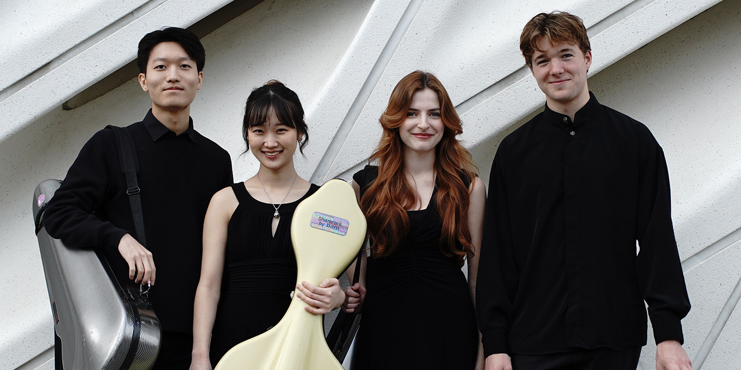 Photo of the Odyssey String Quartet posing with their instruments in front of a modern, sculptural white wall.