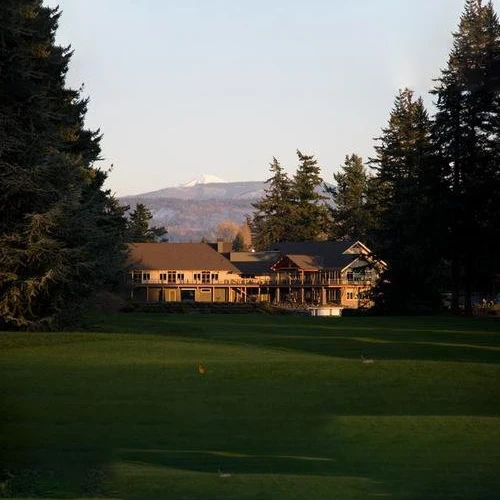 Photo of the Bellingham Country Club clubhouse at dusk, surrounded by evergreen trees.