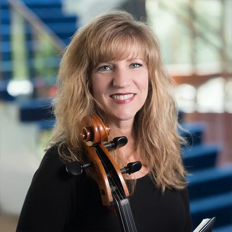 Portrait of Sarah Lewis, cello, standing in front of blue steps.