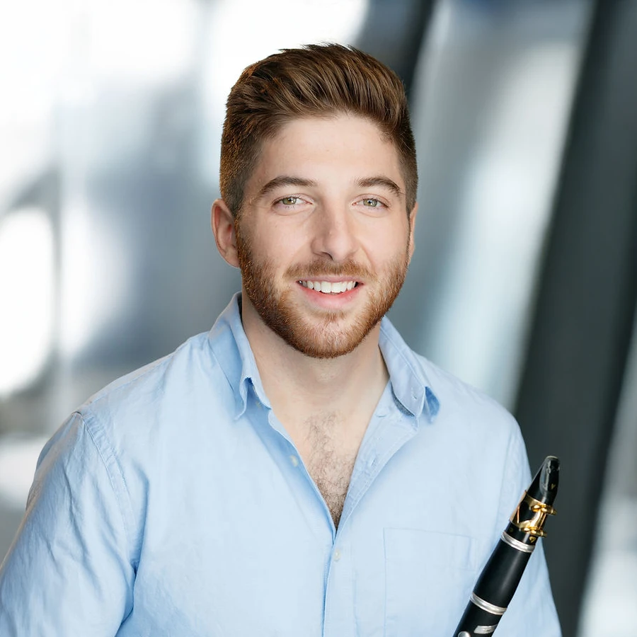 Portrait of Taylor Marino, clarinet in a blue shirt, holding a clarinet.