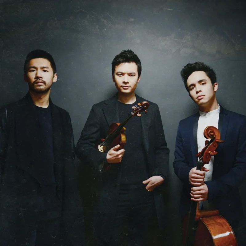 Save the date promotional graphic for The Junction Trio concert at the Bellingham Festival of Music, part of the Sanford Hill Piano Series, scheduled for Saturday, February 21, 2026, at 7:30 p.m. at the WWU Performing Arts Center. Image features the three Junction Trio musicians holding their instruments against a dark background.