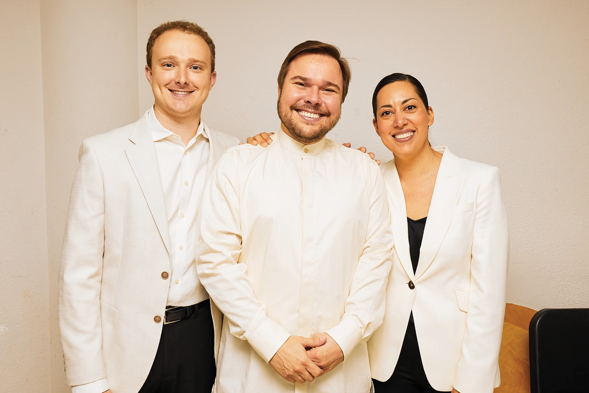 Ryan Dakota Farris, conductor Marcelo Lehninger, and Valery Saul smiling together at the Bellingham Festival of Music Conducting Institute, dressed in coordinated white attire.