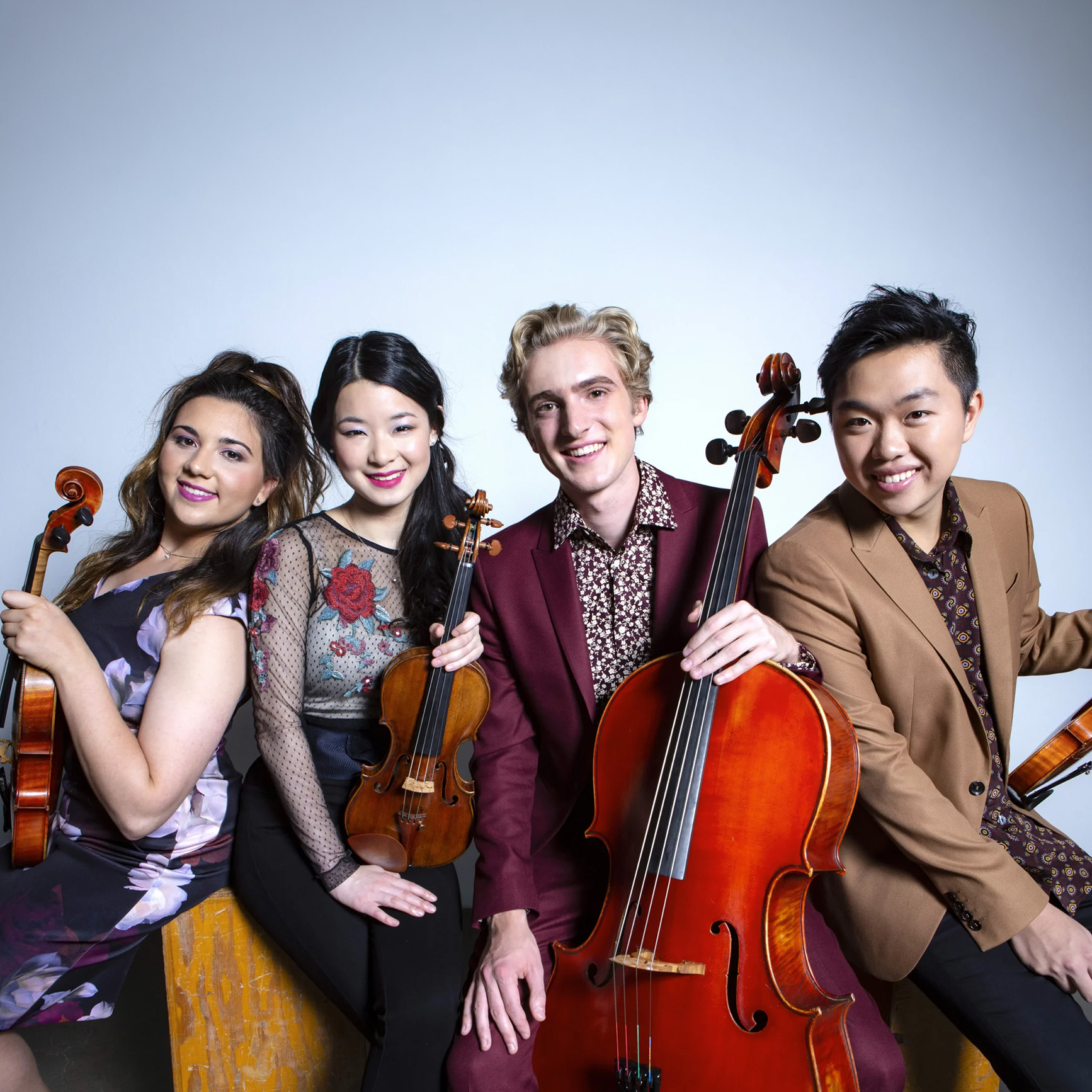 Viano Quartet ensemble members smiling with their string instruments in a formal promotional headshot.