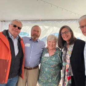 Charlie, Dick Nelson, Sherry Nelson, Sharona, and Daniel posing together under an event tent at an opening party.