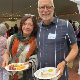 Christina Smith and Paul Murphy holding plates of food and smiling at an outdoor festival opening party in Bellingham.