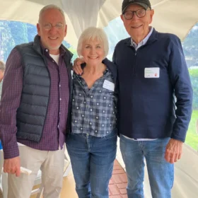 Fred, Annie McCafferty, and Dennis McCafferty posing together inside a white event tent at a Bellingham community gathering.