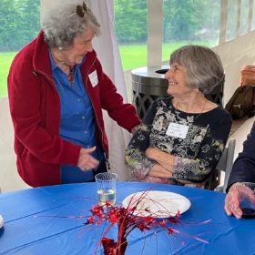Phyllis Self talking with Annette Holcomb at a decorated table during a Bellingham Festival of Music celebration.