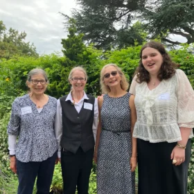 Bellingham Festival of Music volunteers, including Ann and Michelle, standing together in front of a lush garden backdrop.