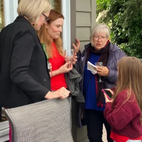 Laura, Erika, and Ella, and Camilla talking with a young girl during an outdoor deck gathering in Bellingham.