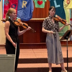 Tessa Lark and Elsa performing a violin duet on stage during a Bellingham Festival of Music community masterclass.