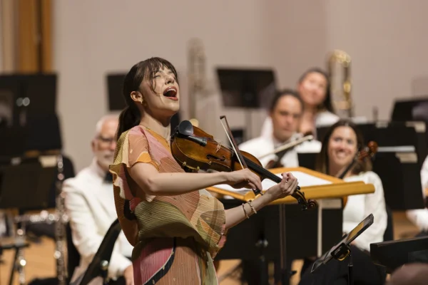 Female violin soloist Tessa Lark performing passionately on stage during a featured orchestral concerto.