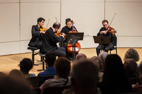 Calidore String quartet featuring violins, viola, and cello performing on stage in front of a live audience during a chamber music concert.